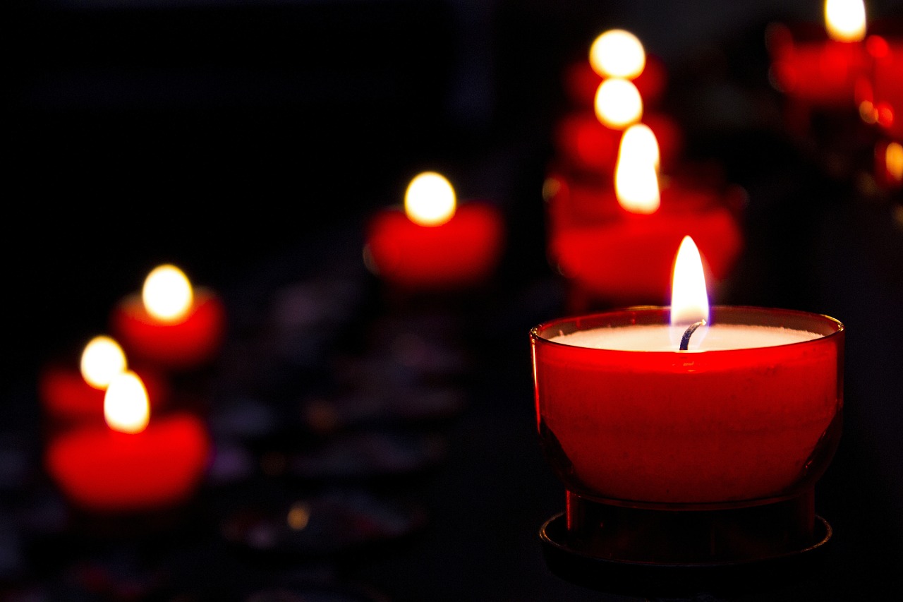 Navigating grief through holidays represented by red candles burning in dark midnight background